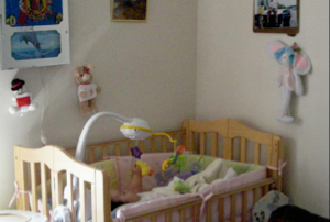 Photo 1:  Note the infant boy lying in his crib and that this apartment is neat and clean as described in the story.